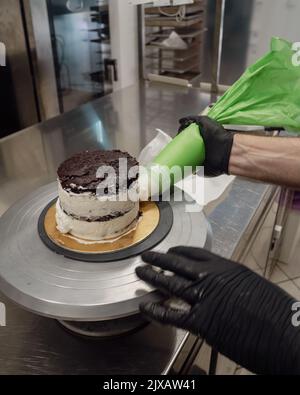 dekorator Buttercreme auf Milchkuchen mit Sahnesack auftragen Stockfoto