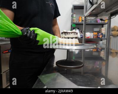 dekorator Buttercreme auf Milchkuchen mit Sahnesack auftragen Stockfoto