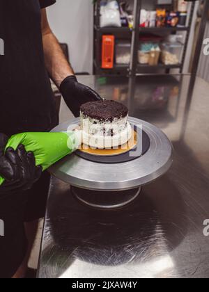 dekorator Buttercreme auf Milchkuchen mit Sahnesack auftragen Stockfoto