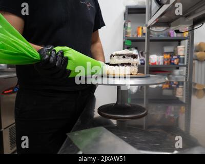 dekorator Buttercreme auf Milchkuchen mit Sahnesack auftragen Stockfoto