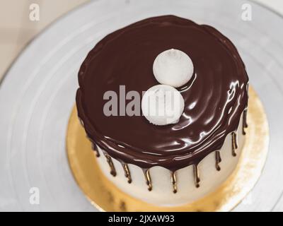 Ein nicht erkennbarer Arbeiter, der einen süßen, tropfenden Schoko-Kuchen und Beeren zubereitet Stockfoto