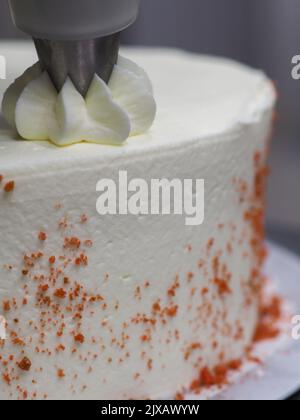 Hand-pof-Koch, der im professionellen Küchelabor einen roten Tropfkuchen zum Anstreichen zaubert Stockfoto