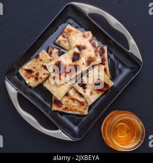 Geröstete Tandoori-Roti mit Schokolade in einem Gericht dunklen Hintergrund Studiofotografie arrangieren Stockfoto