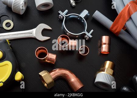 Sanitär und diy mit Material und Werkzeugen auf schwarzem Tisch. Draufsicht. Horizontale Zusammensetzung. Stockfoto