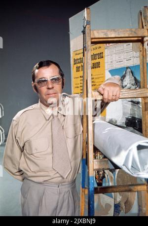 Chris Howland, britischer Schlagersänger, Schauspieler, Fernseh- und Radiomoderator, hängt ein Plakat auf, Deutschland 1975. Stockfoto