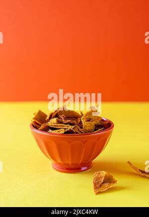 Mangochips in der Schüssel auf gelbem und orangefarbenem Hintergrund Stockfoto