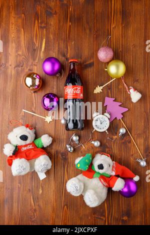 Tjumen, Russland-30. August 2022: Flasche mit Coca-Cola vor weihnachtlicher Hintergrund und Spielzeug für weiße Bären. Flach liegend. Vertikales Foto Stockfoto