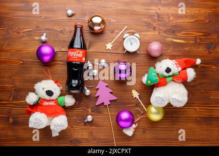 Tjumen, Russland, 30. August 2022: Flasche Coca-Cola im Zimmer, das zu Weihnachten dekoriert wurde. Flach liegend. Holzhintergrund Stockfoto