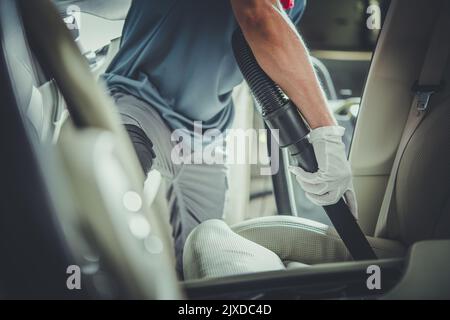 Mitarbeiter Der Fahrzeugreinigung Saugt Ledersitz Auf Der Beifahrerseite Ab. Pflege und Wartung des Fahrzeuginnenraumfahrzeugs. Professionelle Auto Detailing Services Die Stockfoto