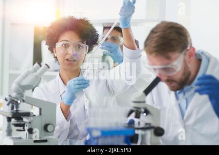 Team von Wissenschaftlern, die mit dem Mikroskop arbeiten und mikrobiologische Proben analysieren Stockfoto