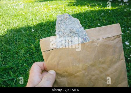POV männliche Hand hält Pakettransport Umschlag aus recycelter Kleidung Stockfoto