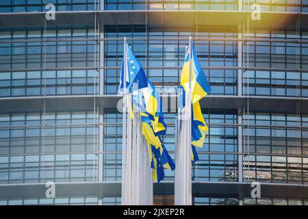 Straßburg, Frankreich - 8. März 2022: Die ukrainische Flagge fliegt neben der Flagge Europas und alle EU-Gewerkschaftsmitglieder Flaggen vor den Büros des Parlamentsgebäudes. Russland setzt seinen Angriff auf die wichtigsten Städte der Ukraine eine Woche nach dem Start einer groß angelegten Invasion des Landes fort Stockfoto