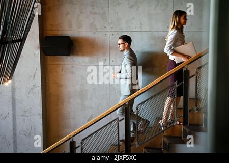 Eine Gruppe von Geschäftsleuten, die in einem Bürogebäude Treppen steigen und gehen Stockfoto