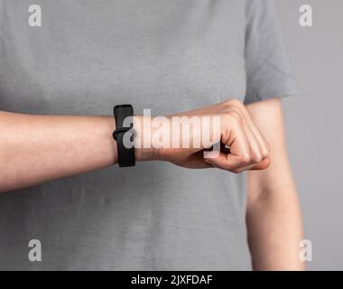 Frau, die Fitness-Tracker für die Überprüfung der Ergebnisse der körperlichen Aktivität sucht. Frau mit Band am Handgelenk für Gehschritte, Laufdistanz, Herzfrequenz oder Stockfoto
