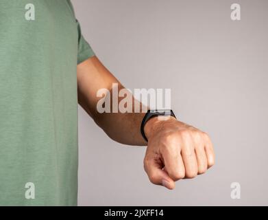Mann mit Blick auf Fitness-Armband für Schritte zu Fuß, Laufdistanz oder Herzfrequenz-Überwachung. Verbesserung des körperlichen Wohlbefindens. Gesunde Lebensweise conce Stockfoto