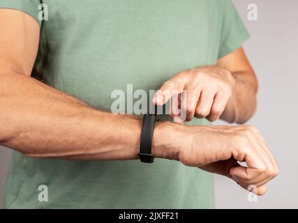 Mann trägt Fitness-Tracker und überprüft die Ergebnisse der körperlichen Aktivität. Herzfrequenzmessung, Anzahl der Schritte zählen. Gesundes Lifestyle-Konzept. Hohe Qua Stockfoto