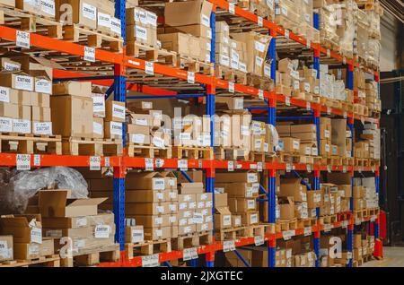 Industrieller Vertrieb, Zusammensetzung. Lagerung mit hohen Fachböden, Ladeboxen in Regalen. Reihen von Regalen mit Kästen im Werk. Stockfoto