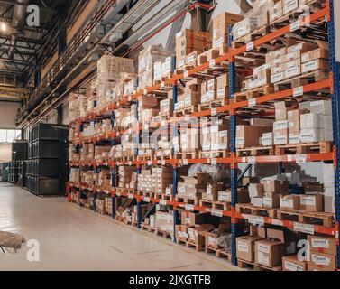 Industrieller Vertrieb, Zusammensetzung. Lagerung mit hohen Fachböden, Ladeboxen in Regalen. Reihen von Regalen mit Kästen im Werk. Stockfoto