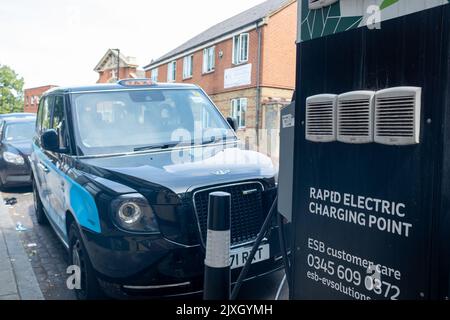 London – 2022. August: Londoner Elektrotaxi an einem Rapid Electric Charging Point an der Streatham High Road im Südwesten Londons Stockfoto