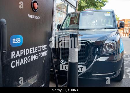 London – 2022. August: Londoner Elektrotaxi an einem Rapid Electric Charging Point an der Streatham High Road im Südwesten Londons Stockfoto