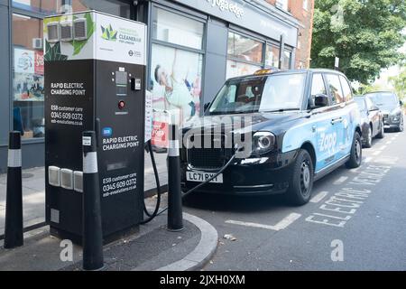 London – 2022. August: Londoner Elektrotaxi an einem Rapid Electric Charging Point an der Streatham High Road im Südwesten Londons Stockfoto