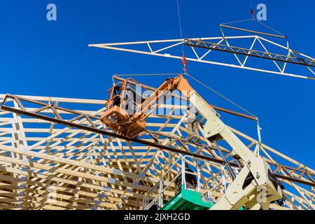 Bauarbeiter mit Lufthammer nagelende Balken aus Holzrahmendach auf Sparren in seinem Haus mit Holzrahmenbalken Stockfoto