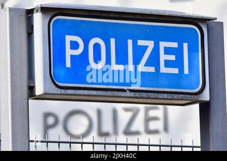 Ein blaues Schild mit der Aufschrift „Poizei“ für „Polizei“ auf einer deutschen Polizeistation. Das Wort steht auch auf dem Gebäude im Hintergrund. Bild aufgenommen Stockfoto