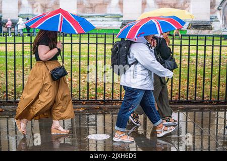 London, Großbritannien. 7. September 2022. Fußgänger, die in Westminster mit Sonnenschirmen laufen, werden in einen sintflutartigen Regenguss verwickelt. Kredit: amer ghazzal/Alamy Live Nachrichten Stockfoto