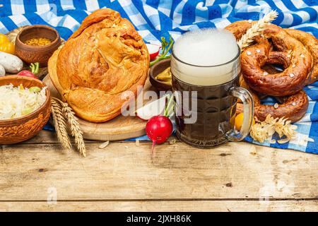 Traditionelles Oktoberfest-Set. Brezeln, Bier, Weisswurst, geräucherter Schweinshaxe eisbein mit fermentiertem Kohl und Senf. Deutsches Festival-Food-Konzept. Stockfoto
