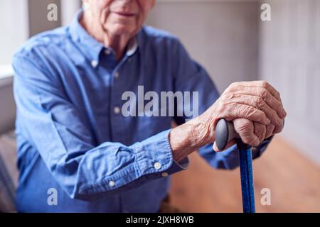 Nahaufnahme Eines Älteren Mannes Zu Hause, Der Sich Die Hände Auf Dem Spazierstock Aufhält Stockfoto