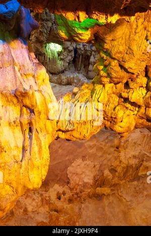 Stalaktitenhöhle, die von farbigen Scheinwerfern auf Hang Dau Go (Wooden Stake Island), einer der vielen Inseln der Halong Bay im Nordosten Vietnams, beleuchtet wird. Stockfoto