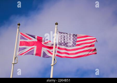 Die Flaggen des Vereinigten Königreichs und der Vereinigten Staaten von Amerika fliegen über einem blauen Himmel in Belfast, Nordirland. Stockfoto