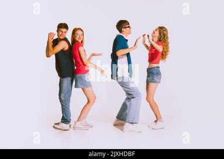 Gruppe junger, fröhlicher, stilvoller Menschen, die isoliert auf grauem Hintergrund tanzen. Freunde treffen sich auf der Party Stockfoto