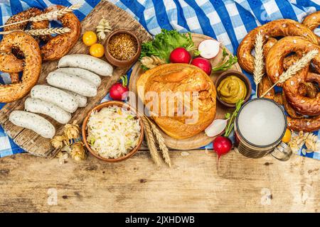 Traditionelles Oktoberfest-Set. Brezeln, Bier, Weisswurst, geräucherter Schweinshaxe eisbein mit fermentiertem Kohl und Senf. Deutsches Festival-Food-Konzept. Stockfoto