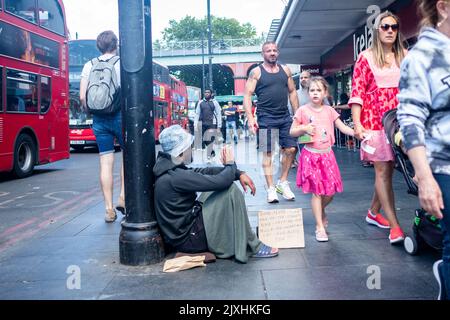 London - August 2022: Ein Obdachloser bettelt auf der Straße von Brixton im Südwesten Londons Stockfoto