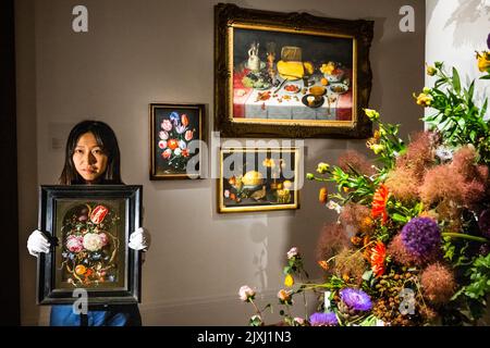 London, Großbritannien. 7. September 2022. Stillleben von Blumen in einer Glasvase in einer Steinnische (est. £1.000.000 - £1.500.000) von Jan Davidsz. De Heem mit Still Life of Luxuries (est. £600.000 - £800.000) von Floris van Dyck und andere Werke im Hintergrund - die Sammlung von Juan Manuel Grasset, holländisch und flämisch, Stillleben in Privatbesitz in Sothebys, New Bond Street. Es wurde im Dialog mit Werken der britischen Künstler Rob und Nick Carter präsentiert und durch Installationen des in Südlondon ansässigen Blumenstudios Sage Flowers ergänzt. Es wird am 7. Dezember im Sotheby's London Old Masters Evening Sale angeboten Stockfoto