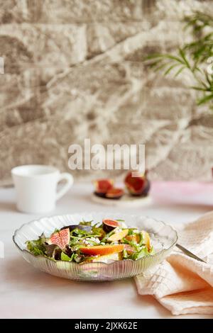 Ästhetischer frischer Salat aus Kartoffeln, Rucola, Getreidekäse, Pfirsich und Feigen. Mediterranes gesundes Gericht, veganer Salat, einfaches Rezept. Stockfoto