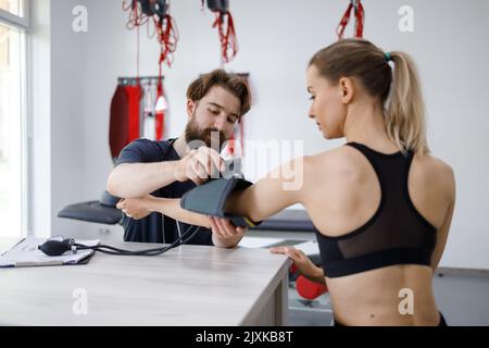 Die junge Frau überprüft den Blutdruck im Büro des Physiotherapeuten Stockfoto