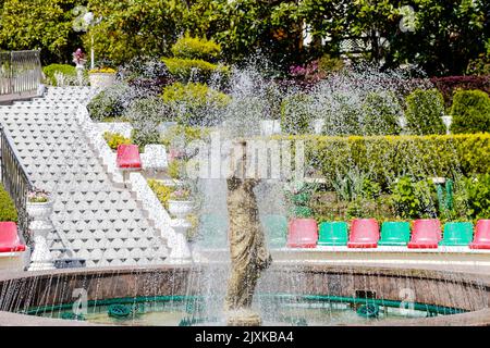 Ein Brunnen ergießt sich über die Statue einer Frau. Wasserspritzer und Steinskulptur eines Mädchens mit Krug Stockfoto