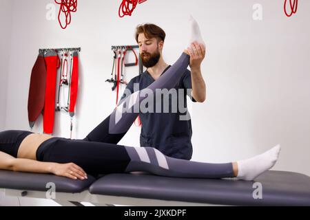 Arzt, der mit einer Patientin in der Klinik arbeitet. Rehabilitation Physiotherapie Stockfoto