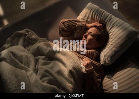 Traurige, reife Frau, die an Depressionen leidet und nachts allein im Bett liegt. Stockfoto