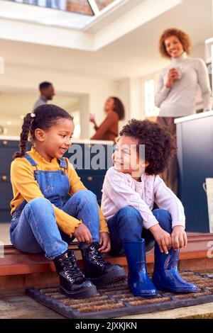 Kinder, Die Zu Hause Auf Der Stufe Sitzen, Ziehen Stiefel An, Bevor Sie Mit Großeltern Auf Einen Familienspaziergang Gehen Stockfoto