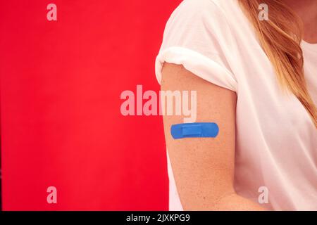 Frau Mit Blauem Klebenden Gips Am Arm Nach Injektion Oder Impfung Gegen Roten Hintergrund Stockfoto