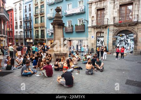 Pamplona, Spanien - Juli 30: Gruppe von glücklichen jungen Menschen, die auf dem Boden sitzen und Bier trinken. Die Freunde genießen eine schöne Zeit zusammen und haben Spaß im N Stockfoto