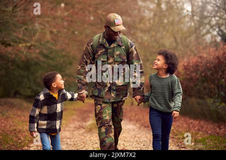 American Soldier In Uniform Kehrt Auf Urlaub Zur Familie Zurück Und Hält Zwei Kinder In Händen Stockfoto