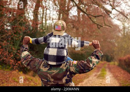 Amerikanischer Soldat Kehrt Nach Hause Zur Familie Zurück, Wenn Er Den Sohn Trägt, Der Von Hinten Eine Armeekappe Trägt Stockfoto
