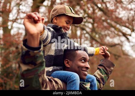 Amerikanischer Soldat In Uniform, Der Auf Urlaub Mit Dem Tragenden Sohn Und Armeekappe Nach Hause Zur Familie Zurückkehrt Stockfoto