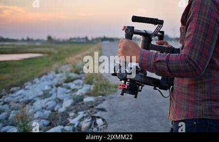 Kameratechniker, der an einem Gimbal arbeitet Wenn Sie Filme auf einem kleinen Set aufnehmen, halten Sie den Stabilisator mit beiden Händen für ein flüssiges Video. Stockfoto