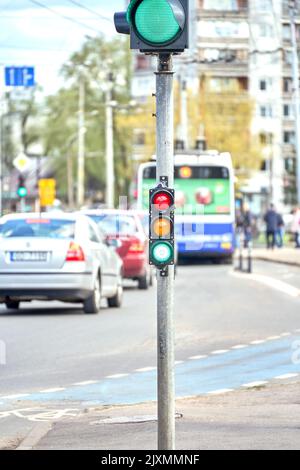 Riga, Lettland - 13. Mai 2022: Kleine Verkehrssemaphore mit grünem Licht vor dem Hintergrund des Stadtverkehrs. Stockfoto