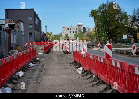 RIGA, LETTLAND - 13. MAI 2022: Rote Kunststoffbarrieren blockieren Bürgersteig unter Reparatur in der Stadt. Stockfoto